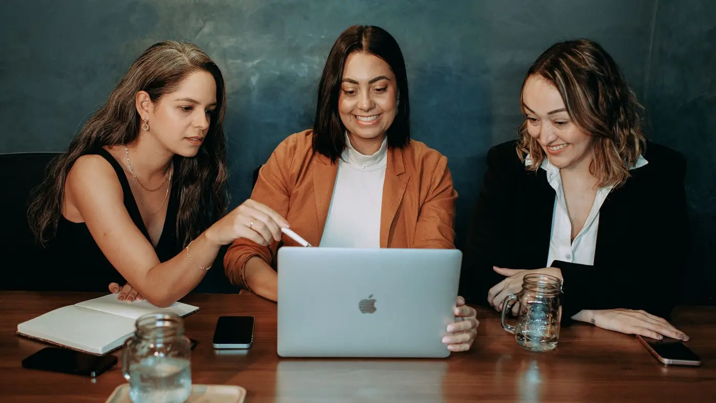 Três mulheres analisando juntas um planejamento no notebook